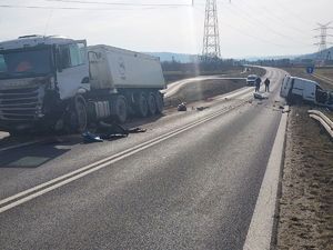 Ogólne miejsce wypadku, z lewej strony widoczny samochód ciężarowy, po prawej stronie biały samochód dostawczy stojący na poboczu