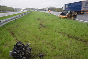 zdjęcie perspektywiczne przedstawiające miejsce wypadku. Na pierwszym planie silnik pojazdu osobowego, wrak osobówki oraz samochód ciężarowy na pasie autostradowym