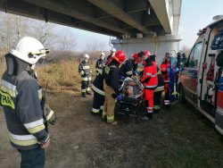 Na noszach mężczyzna obok ratownicy strażacy i ratownicy medyczni