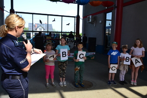 policjantka z grupką dzieci trzymających białe kartki z literami