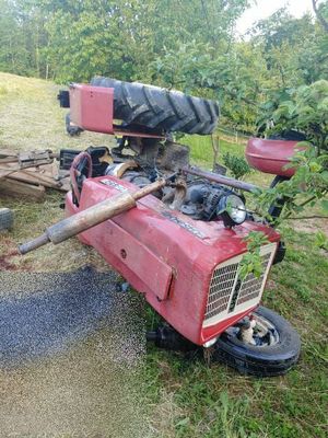 Przewrócony ciągnik rolniczy na prawym boku. zdjęcie zrobione w dzień widoczny przód pojazdu