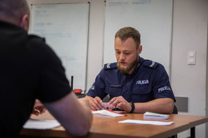 policjant w mundurze siedzi przy biurku