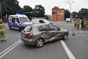 karetka pogotowia oraz samochód osobowy z wgniecionymi drzwiami z prawej strony, dookoła strażacy