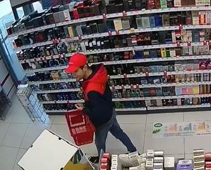 Mężczyzna w czerwonej czapeczce z daszkiem pomiędzy regałami sklepu