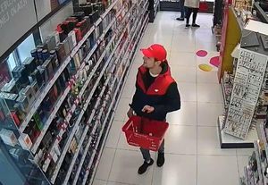 Mężczyzna w czerwonej czapeczce z daszkiem pomiędzy regałami sklepu