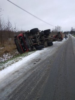 Widok przewróconego samochodu od strony drogi, pokrytej częściowo śniegiem i błotem pośniegowym