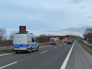 Miejsce kolizji drogowej. Na pierwszym planie radiowóz zabezpieczający jeden pas drogi