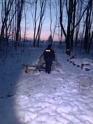 policjant podczas kontroli rozbitego namiotu przysypanego śniegiem