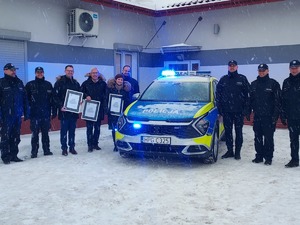 Osoby będące na parkingu przed Komisariatem Policji w Żabnie w trakcie przekazania radiowozu Kia Sportage. Radiowóz ma włączone sygnały świetlne