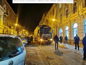 1. Ciężarówka z naczepą na wąskiej ulicy. Interwencja policjantów. Zdjęcie zrobione z przodu.